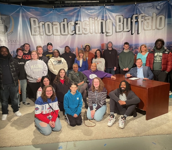 Group of students and professors in front of a sign that reads Broadcasting Buffalo