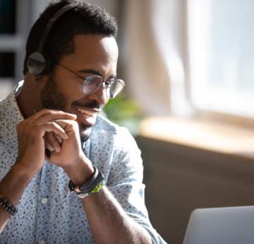 Smiling man with headphones looking at his laptop
