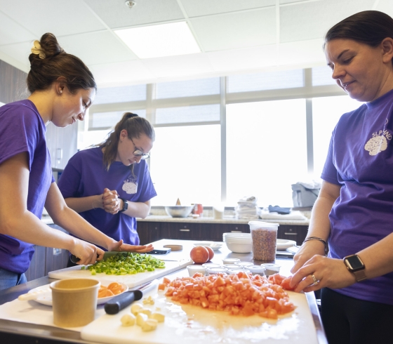 Three female students chopping vegetables